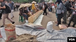 Warga menyaksikan unjuk rasa sembilan perempuan asal Pegunungan Kendeng, Jawa Tengah di depan Istana Negara, Jakarta, Selasa sore 12/4 (VOA/Fathiyah).