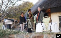 FILE - First lady Michelle Obama stands with daughters Sasha and Malia as she talks with Ian Kirby of Mokolodi Game Reserve before having a private dinner in Gaborone, Botswana, June 24, 2011.