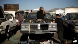 Three men salvage parts gather from a junk car at Aadlen Brothers Auto Wrecking, also known as U Pick Parts, Sun Valley section of Los Angeles, Nov. 11, 2015.