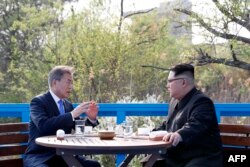 North Korea's leader Kim Jong Un (R) talks with South Korea's President Moon Jae-in (L) at a bench on a bridge next to the military demarcation line at the truce village of Panmunjom on April 27, 2018. The leaders of the two Koreas held a landmark summit