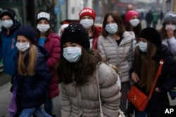 A group of school children walk on street with face mask in Sarajevo, Bosnia, on Wednesday, Dec. 23, 2015.