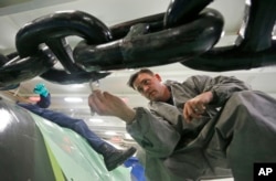 FILE - Navy Seaman Channing Mack, from Pennsylvania, paints a link of an anchor chain during a tour of the nuclear-powered aircraft carrier USS Gerald R. Ford at Newport News Shipbuilding in Newport News, Virginia, April 14, 2016.