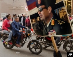 A supporter holds a poster showing President Abdel-Fattah el-Sissi in front of the National Elections Authority in Cairo, Egypt, Jan. 29, 2018.