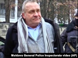 Valentin Grossu is escorted by an armed police officer following his arrest during a cesium smuggling sting operation in Chisinau, Moldova, Feb. 19, 2015.