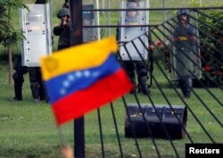 A member of the riot security forces points a gun at an opposition supporter holding a Venezuelan national flag during clashes at a rally against Venezuelan President Nicolas Maduro's government in Caracas, June 22, 2017.