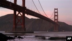 Surfers catch a wave under the Golden Gate Bridge