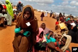 FILE - In this Friday Aug. 5, 2011 file photo, Somali refugees walk through an area housing new arrivals, on the outskirts of Hagadera Camp outside Dadaab, Kenya.