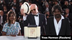 Director Jacques Audiard (C), Palme d'Or award winner for his film "Dheepan", actress Kalieaswari Srinivasan (L) and actor Jesuthasan Antonythasan pose during a photocall after the closing ceremony of the 68th Cannes Film Festival in Cannes, southern Fran