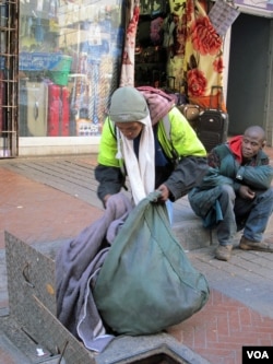 Sello shows his blankets hidden in the drains. His friend Buhlebezwe sits in the background, June 13, 2013 (G. Parker/VOA).