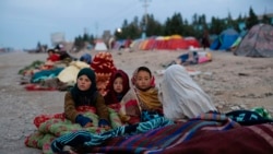 FILE - Afghan children are covered with a blanket as their families camp outside the Directorate of Disaster, in Herat, Nov. 29, 2021.