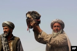 An Afghan man holds up the body of a child that was killed during clashes between Taliban and U.S.-backed Afghan security forces in Kunduz province, in northern Afghanistan, Nov. 3, 2016.