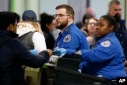FILE - Transportation Security Administration officers work at a checkpoint at Logan International Airport in Boston, Jan. 5, 2019.