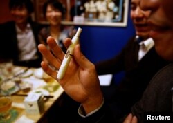 FILE - A man smokes iQOS at a restaurant in Tokyo, Japan, Nov. 2, 2017.