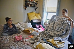 Saturnina Plasencia, 43, folds laundry while talking with her daughter, Ciara, 10, as her newborn, Chloe, sleeps near a window at their home in New York on Monday, Oct. 1, 2018.(AP Photo/Bebeto Matthews)