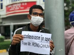 A youth holds a banner calling for the release of Rong Chhun in front of the Olympia Mall of Phnom Penh, August 3, 2020. (Hul Reaksmey/VOA Khmer)