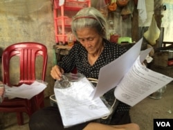 "Mommy" is siting in front of her house looking for documents proving the house belongs to her family after she was released in April. (Phorn Bopha/VOA Khmer)