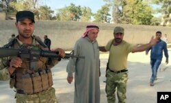 In this image made from video posted online by Qasioun News Agency, Turkish-backed Syrian opposition forces allow a man to pass after being searched, in Dabiq, Syria, Oct. 16, 2016.