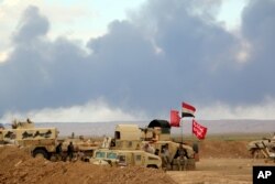 FILE - Smoke rises as the Iraqi army, supported by Iranian-backed Shiite militias and Sunni tribes, battles Islamic State extremists outside Tikrit, 80 miles (130 kilometers) north of Baghdad, Iraq, March 4, 2015.