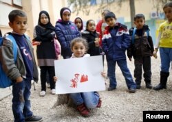 FILE - Syrian refugee Tesnim Faydo, 8, shows her drawing of a mother crying for her wounded daughter, as she is surrounded by her friends in Yayladagi refugee camp in Hatay province near the Turkish-Syrian border, Turkey, Dec. 16, 2015.