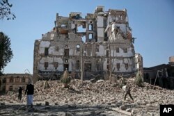 FILE - Houthi Shi'ite rebels walk amid the rubble of the Republican Palace that was destroyed by Saudi-led airstrikes, in Sana'a, Yemen, Dec. 6, 2017.