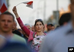 A Belarusian protester waves an opposition flag during a rally after parliamentary election in Minsk, Belarus, Sept. 12, 2016. About 150 Belarusian opposition activists gathered for an unauthorized rally under the slogan "We demand real elections."