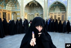 An Iranian woman displays her ink-stained finger after voting in the parliamentary and Experts Assembly elections at a polling station in Qom, Feb. 26, 2016.