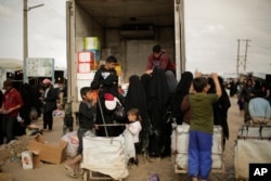 FILE - In this March 31, 2019, photo, women purchase goods from the back of a truck in the marketplace at al-Hol camp, near Hasakah, Syria. Al-Hol camp is home to thousands of people who streamed out of the Islamic State group’s last strongholds.