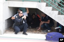 Law enforcement personnel shield civilians outside a garage area at Fort Lauderdale-Hollywood International Airport in Fort Lauderdale, Fla., Jan. 6, 2017. A gunman opened fire in the baggage claim area at the airport Friday, killing several people.
