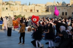 Anak-anak Palestina bermain saat sholat Idulfitri, di kompleks yang menampung masjid al-Aqsa, yang dikenal oleh Muslim sebagai Tempat Suci dan Orang Yahudi sebagai Temple Mount, di Kota Tua Yerusalem , di tengah pertempuran Israel-Gaza 13 Mei 2021.