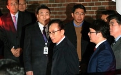 Mantan Presiden Korea Selatan Lee Myung-bak, tengah, masuk ke dalam mobil saat ia dipindahkan ke pusat penahanan, di kediamannya di Seoul pada Jumat pagi, 23 Maret 2018. (Foto: AP)