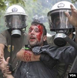 Polisi anti-huru-hara menahan seorang pengunjuk rasa di Lapangan Konstitusi, Athena, Rabu (29/6).