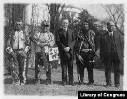This 1925 photo shows President Calvin Coolidge posed with unidentified Native Americans, near the south lawn of the White House, shortly after passage of the Native American Citizenship Act of June 1924.
