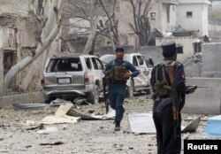 FILE - An Afghan policeman runs during the gunfire in front of the Indian consulate in Jalalabad, Afghanistan, March 2, 2016.