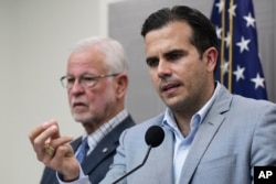 Flanked by Public Safety Secretary Hector Pesquera, Puerto Rico Gov. Ricardo Rossello speaks during a press conference regarding the aftermath of Hurricane Maria, in San Juan, Puerto Rico, Aug. 28, 2018.