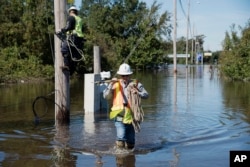 A lineman works to restore power lines near I-95 after the area was flooded by rain from Hurricane Matthew in Lumberton, North Carolina, Oct. 11, 2016.