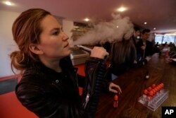 FILE - Talia Eisenberg, co-founder of the Henley Vaporium, uses her vaping device in New York, Feb. 20, 2014.
