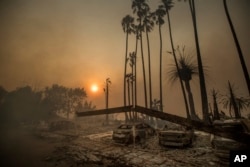 Smoke rises behind a leveled apartment complex as a wildfire burns in Ventura, Calif., on Tuesday, Dec. 5, 2017.