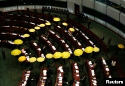 FILE - Pro-democracy lawmakers carrying yellow umbrellas, symbols for the Occupy Central movement, leave in the middle of a Legislative Council meeting as a gesture to boycott the government in Hong Kong, January 7, 2015.