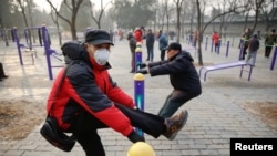 A man wearing a face mask exercises in a park despite a red alert issued for air pollution in Beijing, China, Dec. 18, 2016.