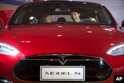 FILE - A man sits in a Tesla Model S electric car on display at a Beijing auto show, April 25, 2016. In May, a Tesla on "autopilot'' crashed into a truck that was turning, drawing attention to the limitations of self-driving technology.