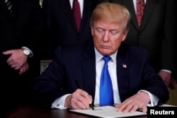 FILE - U.S. President Donald Trump signs a memorandum on intellectual property tariffs on high-tech goods from China, at the White House in Washington, March 22, 2018.