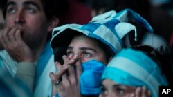Argentina soccer fans react as they watch via a live broadcast the World Cup final match between Argentina and Germany on an outdoor television screen in Buenos Aires, Argentina, July 13, 2014.