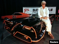 FILE - Actor Adam West, who portrayed the title character in the 1960s television series "Batman," poses atop the original Batmobile used in the show.