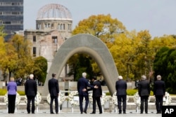 FILE - U.S. Secretary of State John Kerry, center left, puts his arm around Japan's Foreign Minister Fumio Kishida, center right, after they and fellow G7 foreign ministers laid wreaths at the cenotaph at Hiroshima Peace Memorial Park in Hiroshima, Japan.