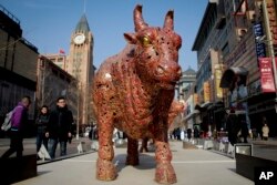 People walk by bull sculptures titled "Five Bulls Gathering Fortune" on display at the Wangfujing shopping district in Beijing, Jan. 10, 2019.
