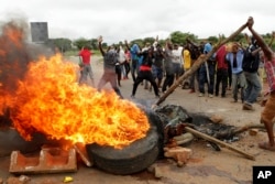 FILE - Protesters gather near a burning tire during a demonstration over the hike in fuel prices in Harare, Zimbabwe, Jan. 15, 2019.