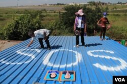 ពលរដ្ឋ​នៅ​ភូមិ​ត្រពាំង​ល្វា​ក្នុង​សហគមន៍​អាកាស​យានដ្ឋាន​អន្តរ​ជាតិ​ភ្នំពេញ​ដែល​ហៅ​កាត់​ថា «SOS» នាំ​គ្នា​សរសេរ​អក្សរ​ថា «SOS» លើ​ដំបូល​ផ្ទះ​របស់​ពួក​គេ ដើម្បី​ឲ្យ​មាន​ការ​ចាប់​អារម្មណ៍​ពី​លោក ហ៊ុន សែន ពេល​លោក​ត្រលប់​មក​ពី​កិច្ចប្រជុំ​កំពូល​អាស៊ាន នៅ​ថ្ងៃ​ទី១៣ ខែវិច្ឆិកា ឆ្នាំ២០១៤។