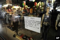 FILE - A sign in the window of a closed clothing store in a Latino mall in Atlanta, July 1, 2011, shows support for "A Day Without Immigrants," in which a Georgia Latino group is calling on businesses to close and community members to not work or shop.