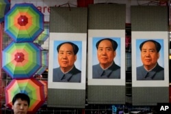 FILE - A salesperson sits near posters of the late communist leader Mao Zedong on display for sale at a shop near Tiananmen Square in Beijing, Sept. 9, 2016.