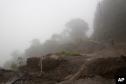 Neighbors walk in the rain from Tropical Storm Nate that helped wash out a road in Alajuelita, Costa Rica, Oct. 5, 2017.